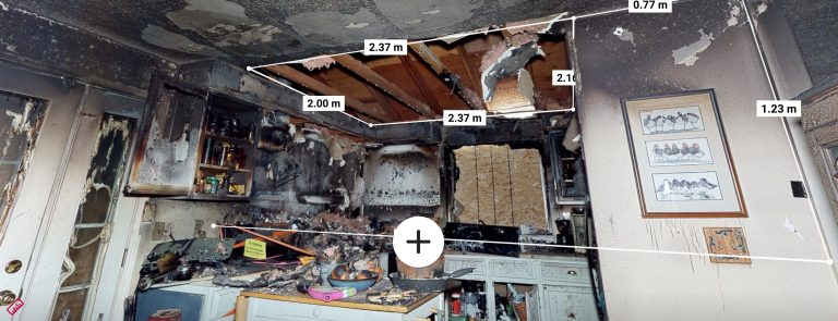 Cuisine sinistrée après incendie avec mesures 3D visibles — plafond effondré, suie sur les parois, mobilier brûlé — relevés numériques utilisés pour expertise judiciaire et constat 3D